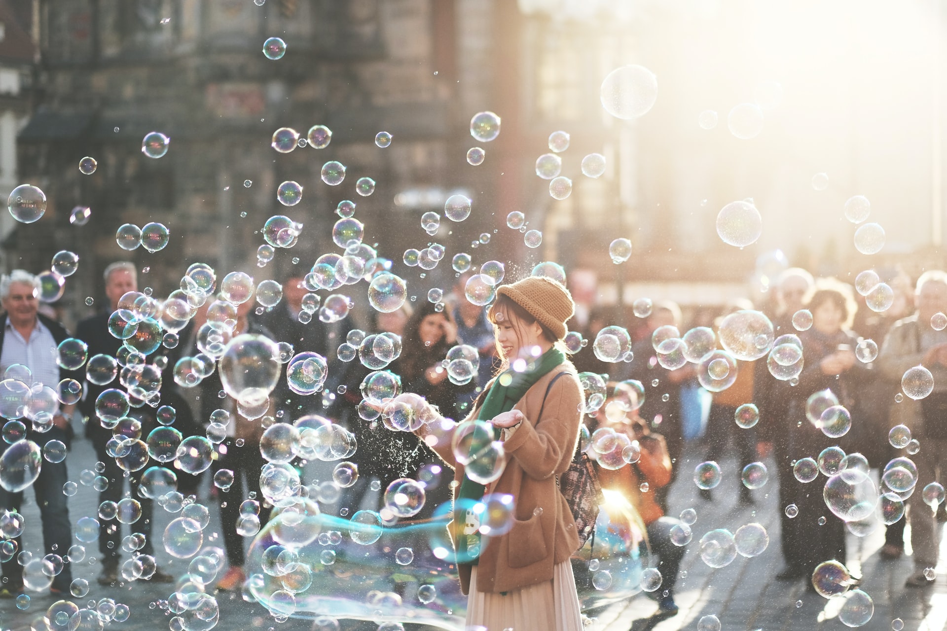 capture the moment photograph, person stands happily among lots of bubbles, onlookers in urban background