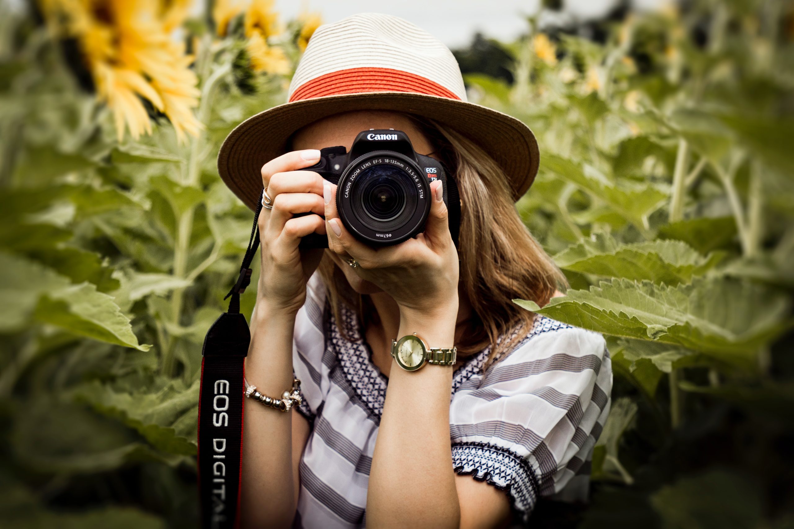 Person standing outside among bushes taking photo with their Canon camera