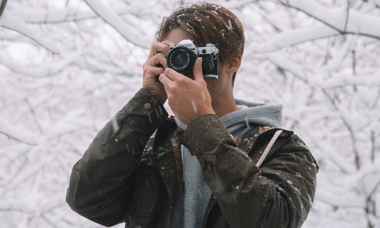 Photographer out in the snow using a Canon camera to photograph something out of sight