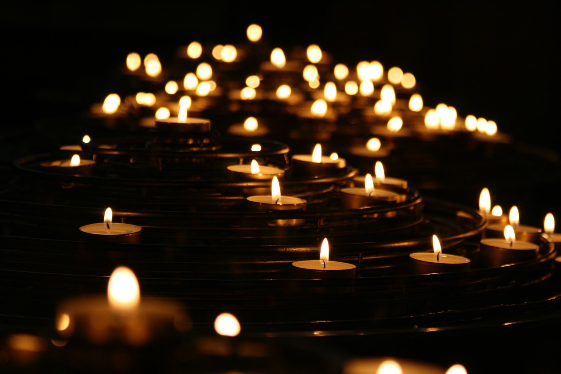 Photograph of candles in dark water, ripples surrounding