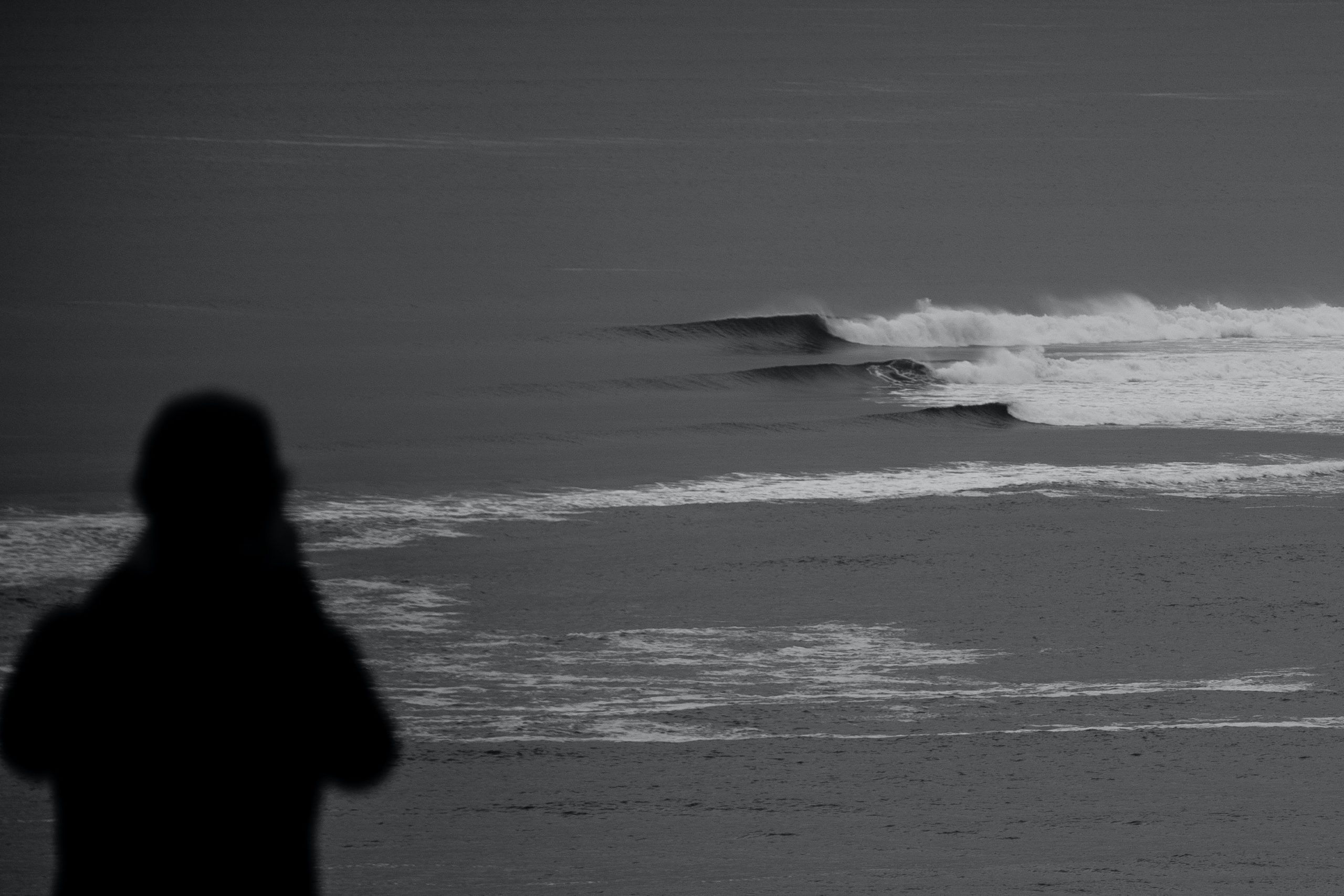 Black and white photo using the rule of thirds, showing a silhouette against a crashing wave