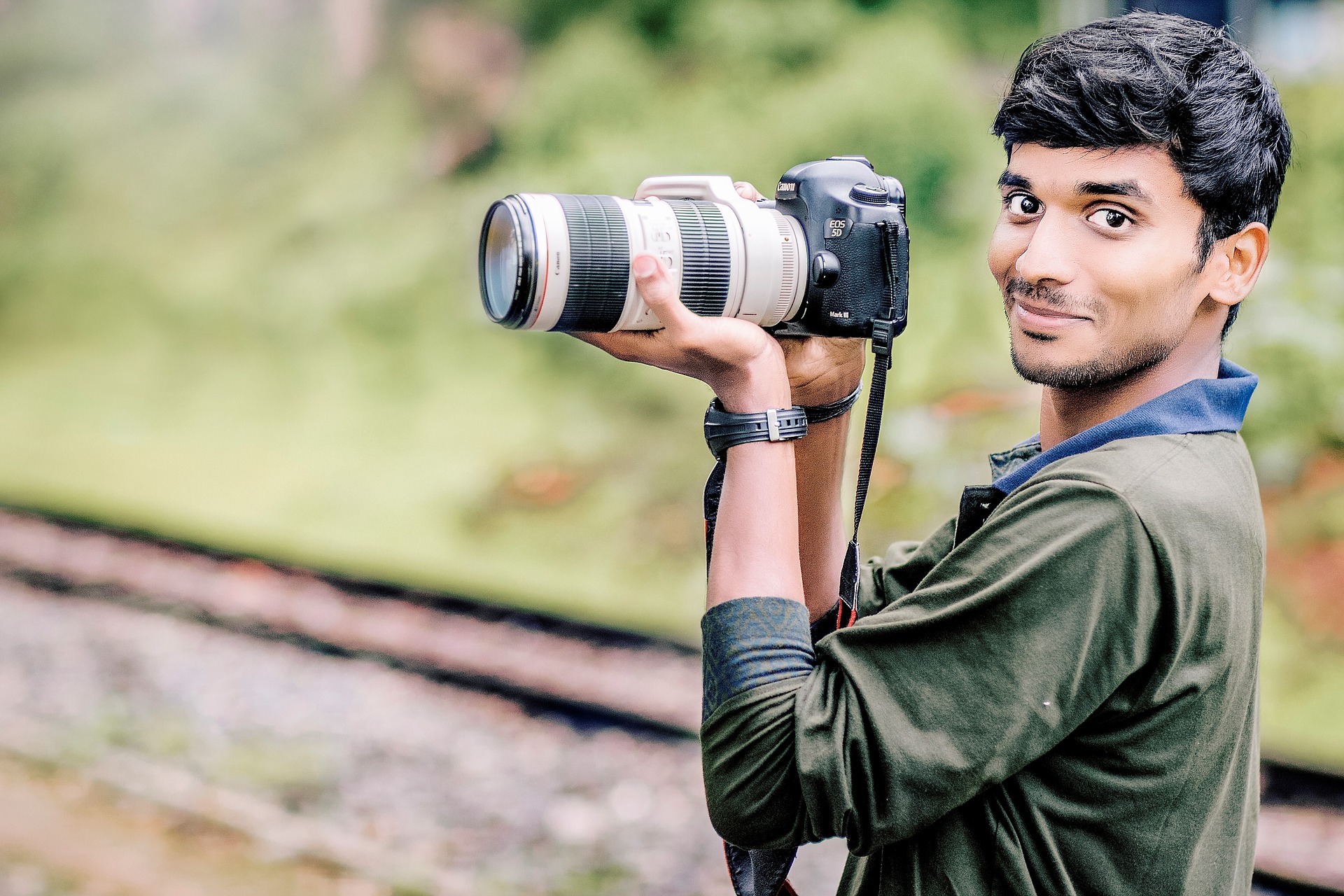 Smiling photographer holding a DSLR camera, looking at the viewer