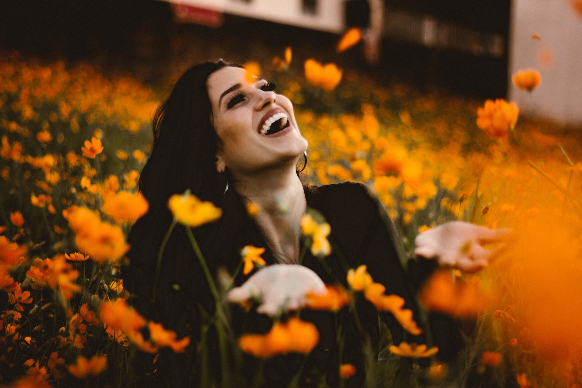 Person with a natural smile having fun among field of autumnal flowers
