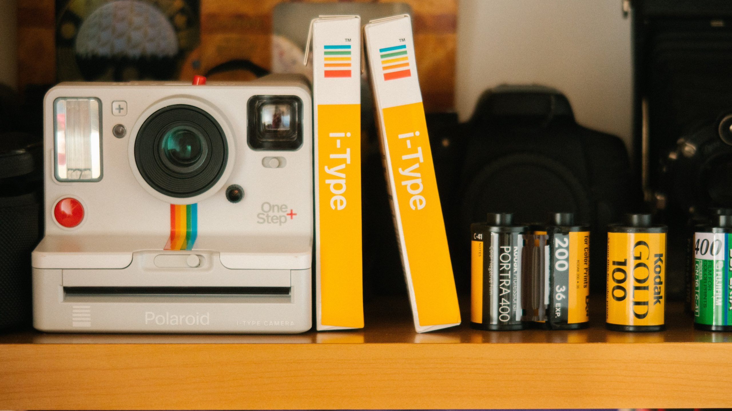 A Polaroid instant camera on a shelf next to film