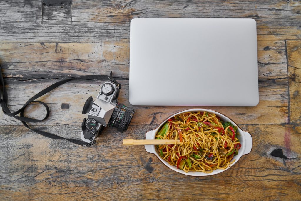 high quality camera on table beside food and laptop